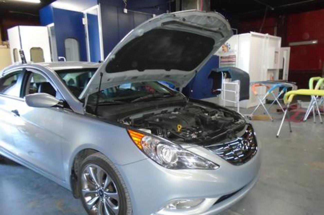 A sedan in the repair bay with the hood raised